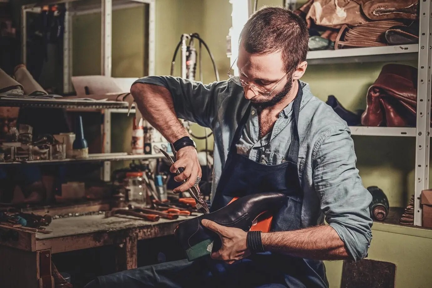 A skilled cobbler is working on a pair of black men's shoes at his workshop.