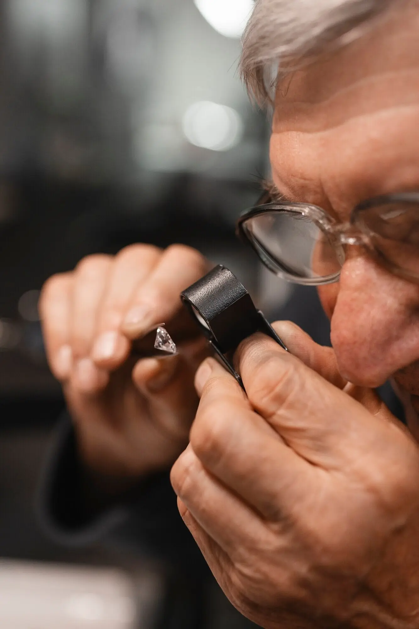 A male jeweler at work in the shop with a magnifying glass.